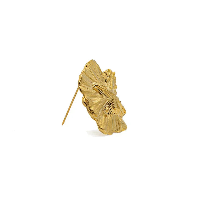 Pendiente dorado forma de hoja con textura orgánica sobre fondo blanco