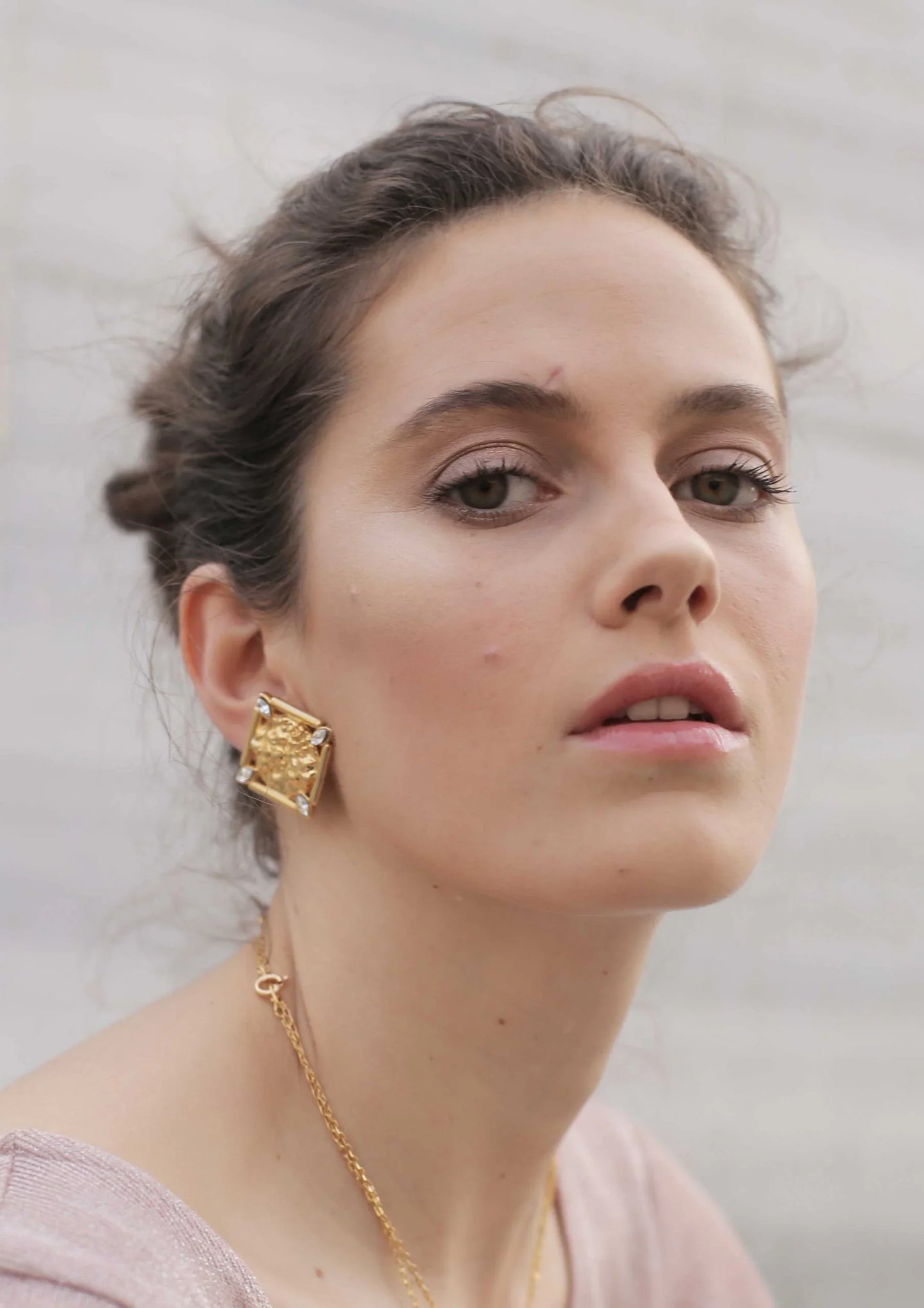 Mujer con pendiente cuadrado dorado de estilo moderno y elegante, fondo claro difuminado